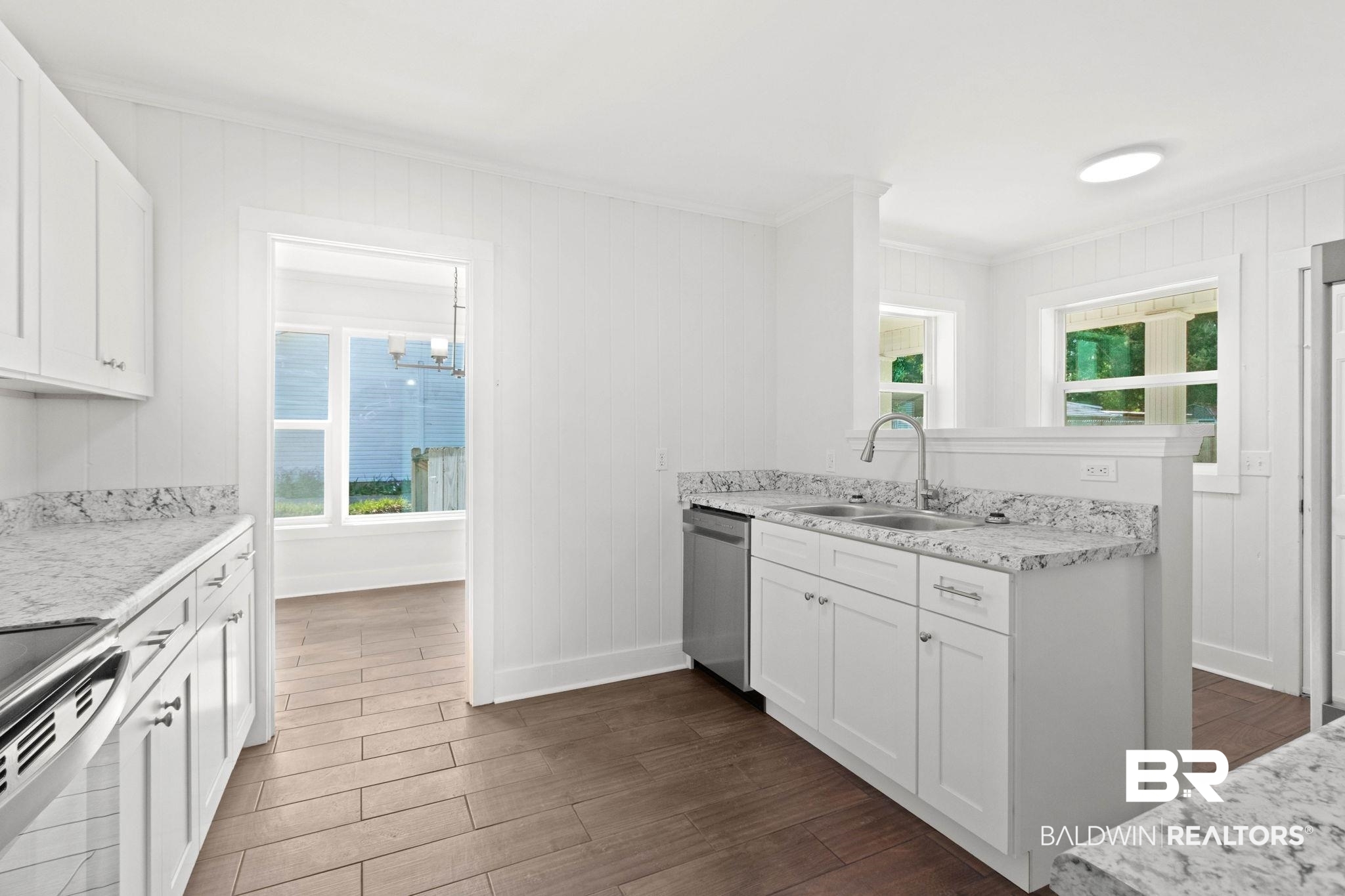 311 Cloverdale Road Atmore, AL 36502 - Photo 21 of 63 Bright kitchen featuring white cabinetry, granite-finish countertops, stainless steel appliances, a double basin sink with a gooseneck faucet, and wood-finish tile flooring