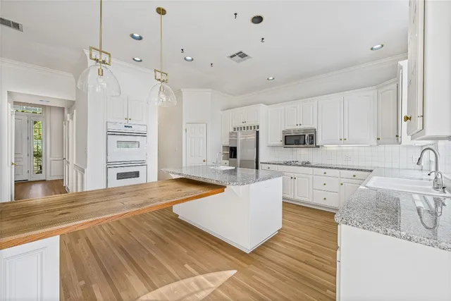 a large kitchen with kitchen island a stove a sink a center island and cabinets