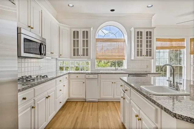 a kitchen with granite countertop a sink white cabinets and stainless steel appliances