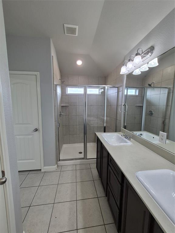 8050 Privet Street Forney, TX 75126 - Photo 13 of 24 This bathroom features a double vanity with two sinks, a spacious shower with a glass enclosure, and tile flooring
