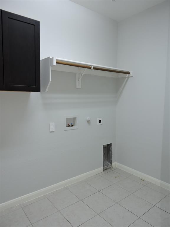 8050 Privet Street Forney, TX 75126 - Photo 20 of 24 Utility room with tile flooring, a dark cabinet, and a wall-mounted hanging rod