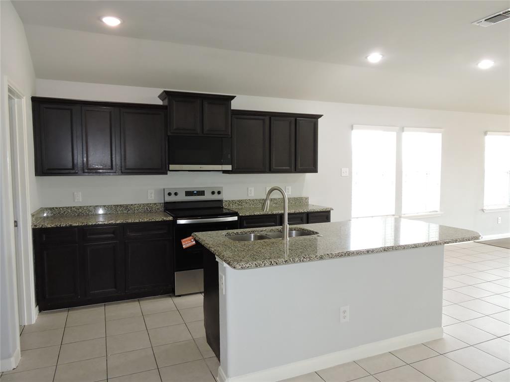 8050 Privet Street Forney, TX 75126 - Photo 5 of 24 The kitchen features dark cabinetry, speckled countertops, a stainless steel sink, and an electric range with an overhead microwave
