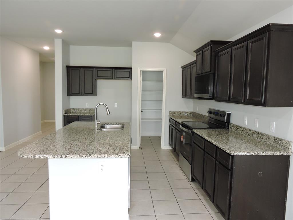 8050 Privet Street Forney, TX 75126 - Photo 6 of 24 The kitchen features dark wood cabinetry, granite countertops, stainless steel appliances, and a central island with an integrated sink
