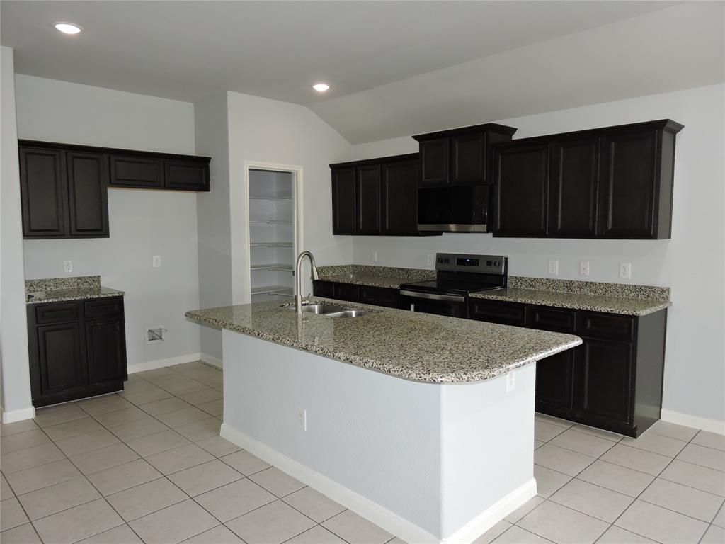 8050 Privet Street Forney, TX 75126 - Photo 7 of 24 Kitchen featuring an island with a sink and a gooseneck faucet, dark cabinetry, light-colored granite countertops, and tile flooring