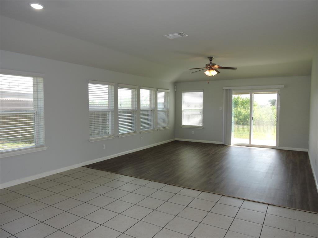 8050 Privet Street Forney, TX 75126 - Photo 8 of 24 Spacious room featuring a combination of tiled and wood-look flooring, a ceiling fan, recessed lighting, and ample natural light from multiple windows and a sliding glass door
