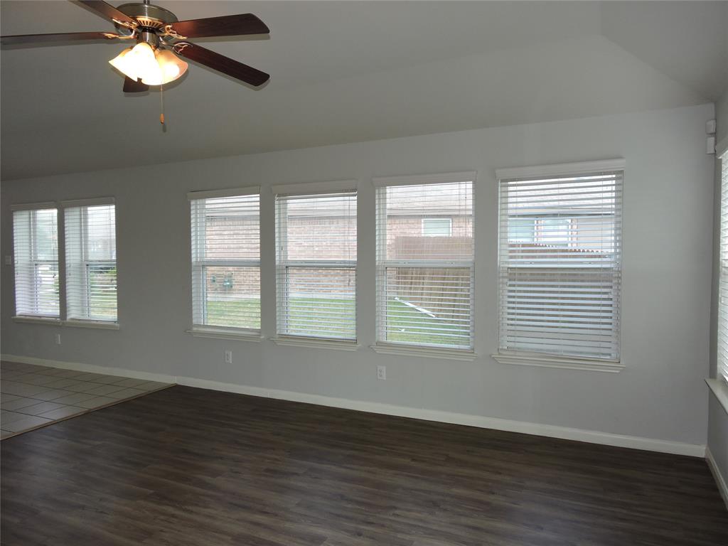 8050 Privet Street Forney, TX 75126 - Photo 10 of 24 Living area featuring wood-look flooring, multiple windows with blinds, and a ceiling fan with integrated lighting