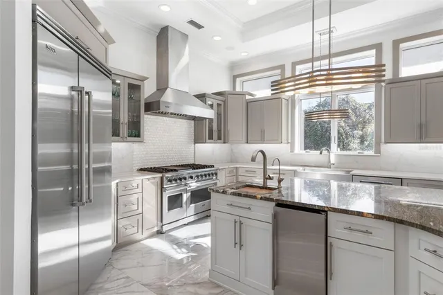 a kitchen with stainless steel appliances granite countertop a refrigerator a stove and a sink