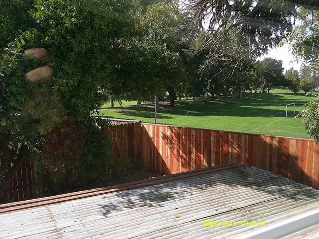 a view of backyard with wooden fence and plants