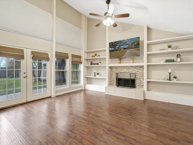 an empty room with wooden floor fireplace and windows