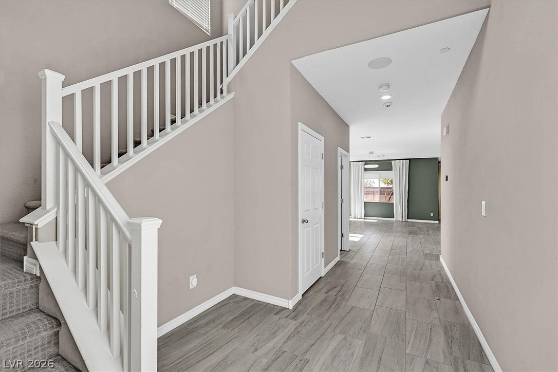 1106 Langston Ranch Avenue Henderson, NV 89002 - Photo 3 of 36 A graceful staircase with carpeted treads ascends alongside a tiled hallway leading to a bright living space.