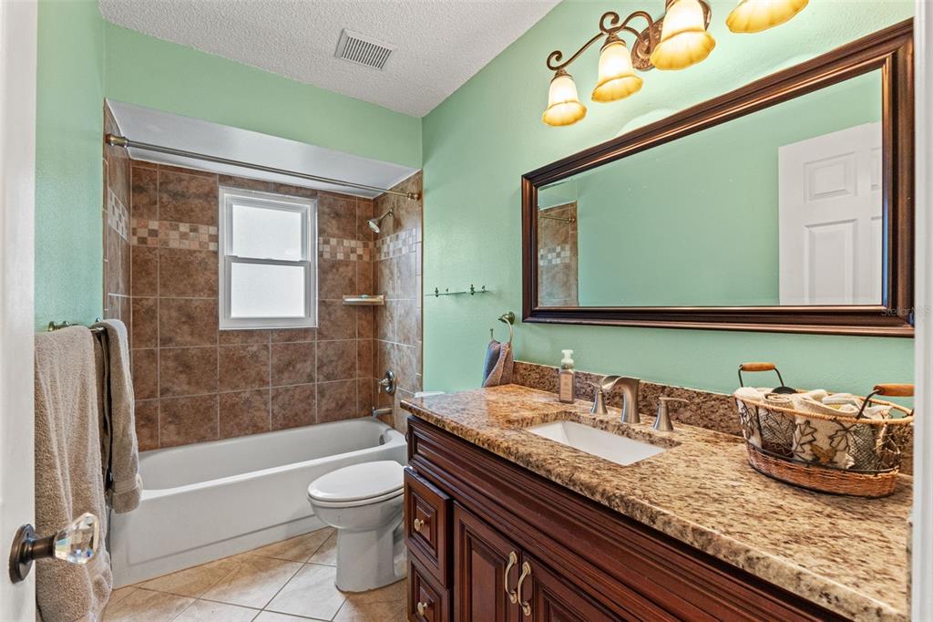7828 Hardwick Drive, Unit 924 New Port Richey, FL 34653 - Photo 16 of 35 a bathroom with a granite countertop sink a toilet a mirror and bathtub