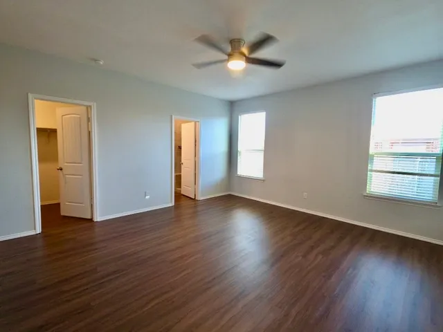 an empty room with wooden floor and windows