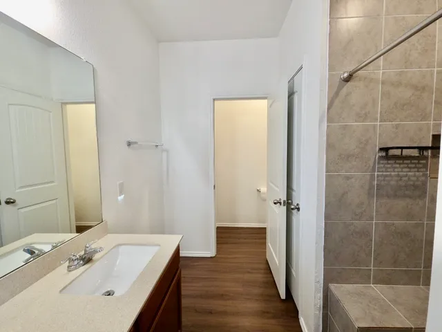 an empty room with wooden floor and a ceiling fan