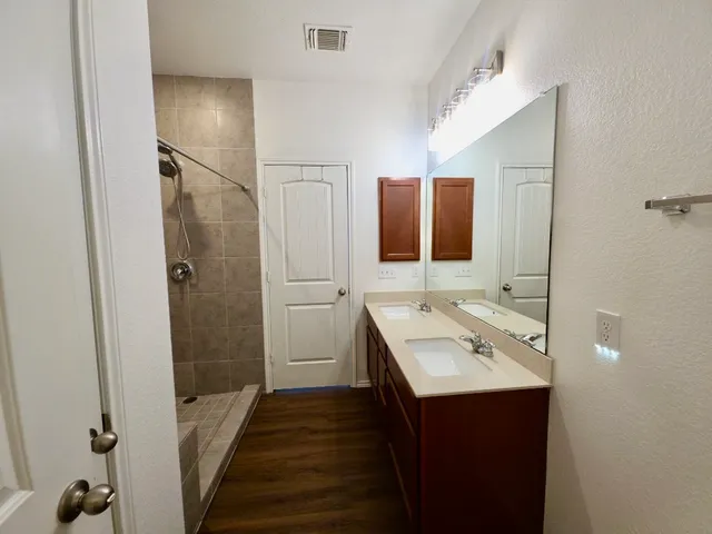 a bathroom with a tub sink vanity granite and shower