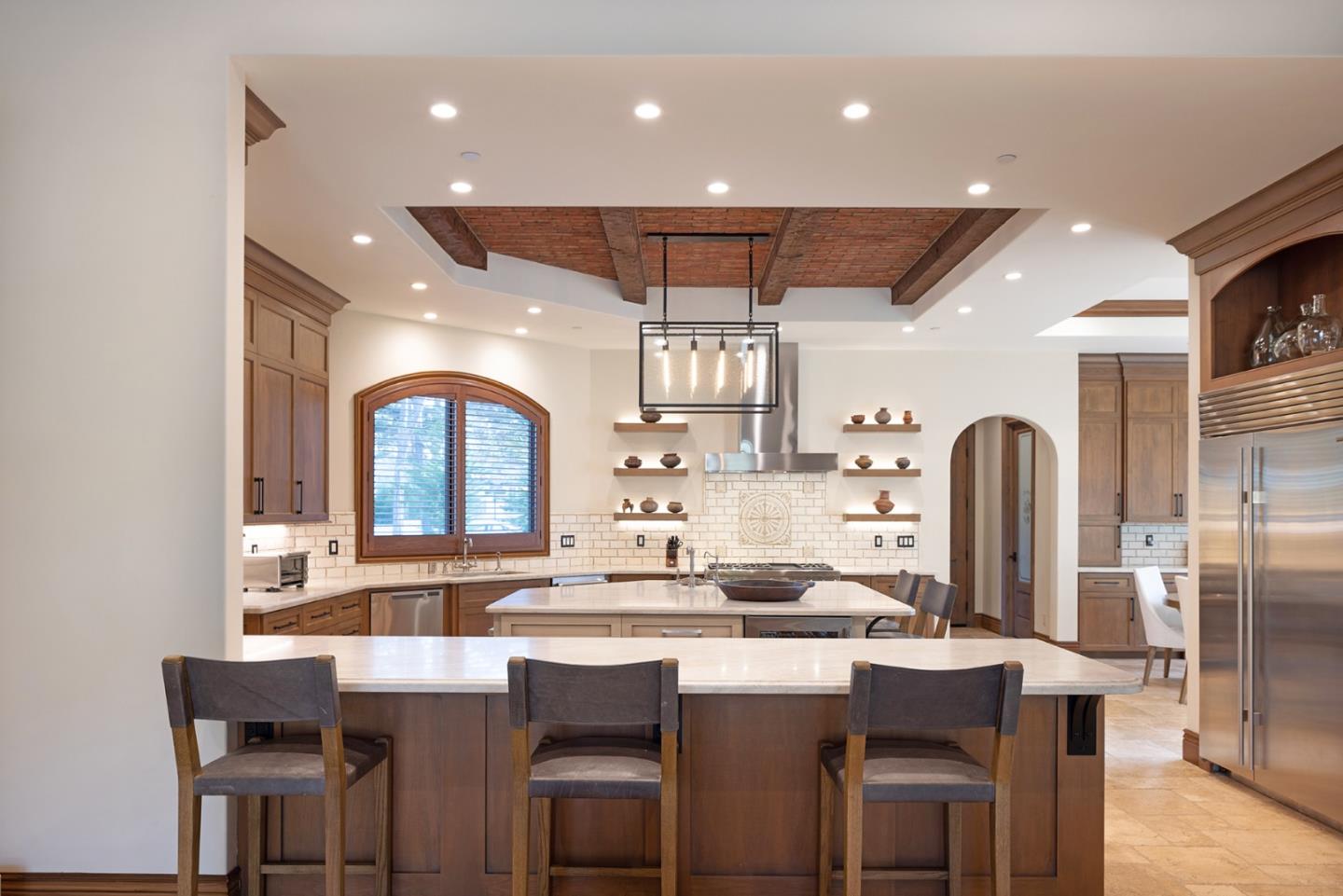 1437 Viscaino Road Pebble Beach, CA 93953 - Photo 8 of 30 a kitchen with stainless steel appliances kitchen island granite countertop a table chairs in it and wooden floors