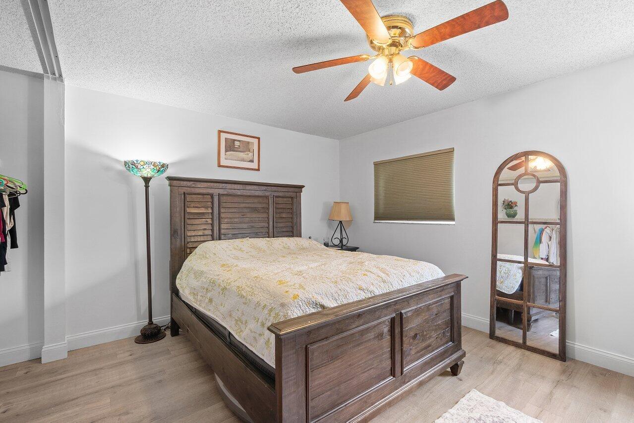 6199 Riverwalk Lane, Unit 6 Jupiter, FL 33458 - Photo 17 of 33 a bedroom with a bed and a chandelier