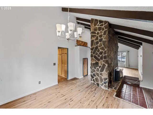 a view of a livingroom with wooden floor and kitchen view