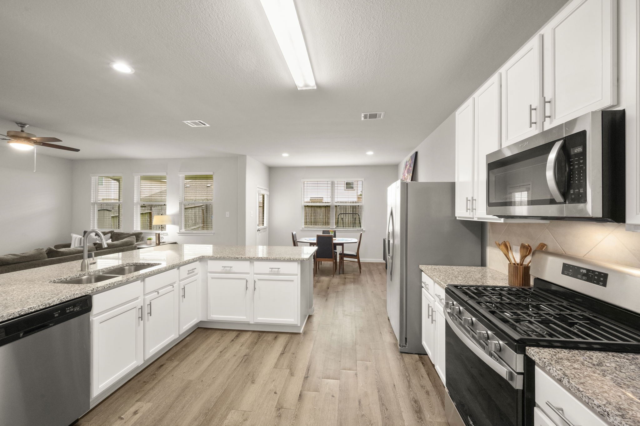 4915 Blue Jacaranda Way Spring, TX 77373 - Photo 8 of 30 Sleek touches in this kitchen - shaker-style cabinets, granite counters, stainless steel appliances, cabinet pulls and an upgraded pull-down faucet.