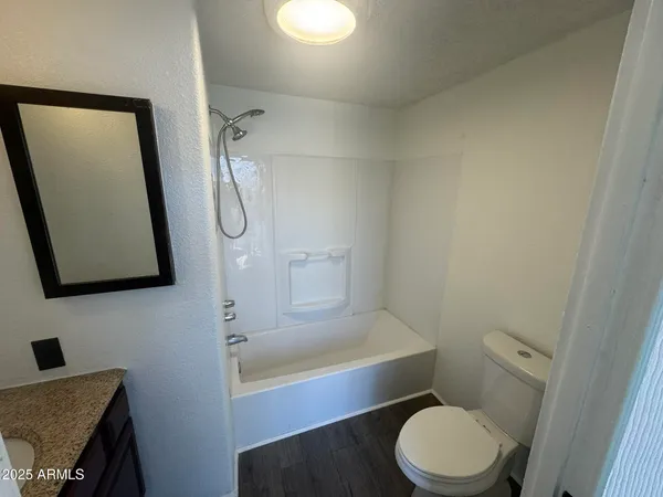 a bathroom with a granite countertop sink a mirror and a bathtub