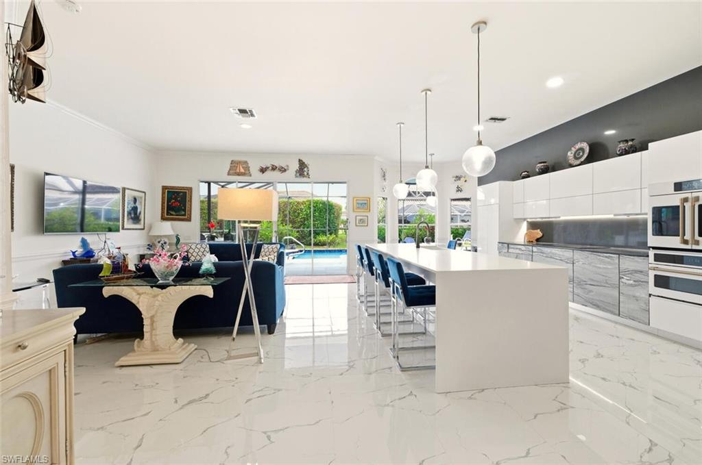 209 Countryside Drive Naples, FL 34104 - Photo 48 of 50 a living room with furniture a chandelier and a flat screen tv