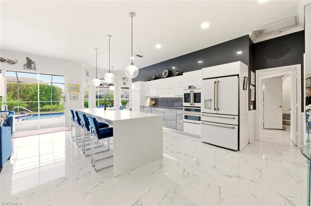 209 Countryside Drive Naples, FL 34104 - Photo 7 of 50 a kitchen with stainless steel appliances kitchen island granite countertop a refrigerator a oven and white cabinets with wooden floor