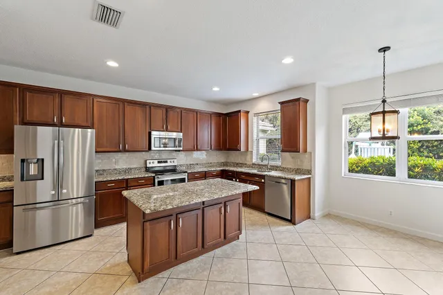 an empty room with wooden floor ceiling fan and windows