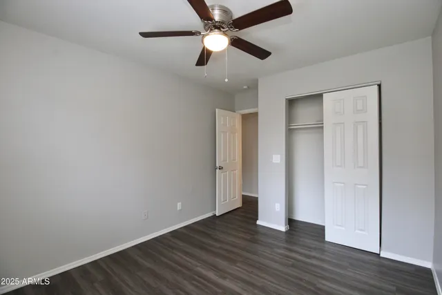 an empty room with wooden floor a ceiling fan and closet