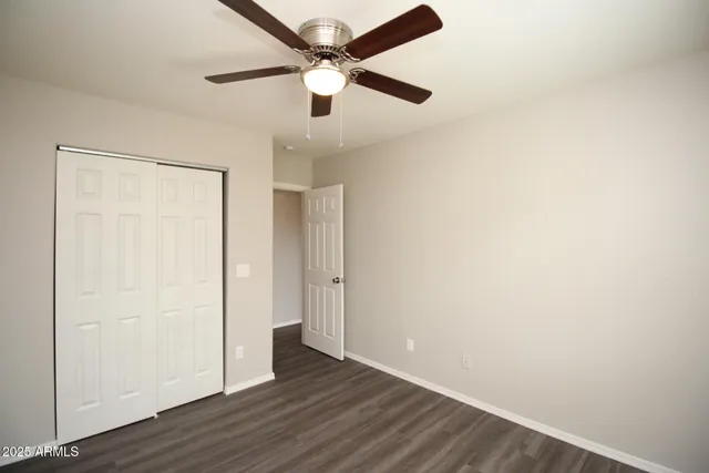 an empty room with wooden floor a ceiling fan and closet