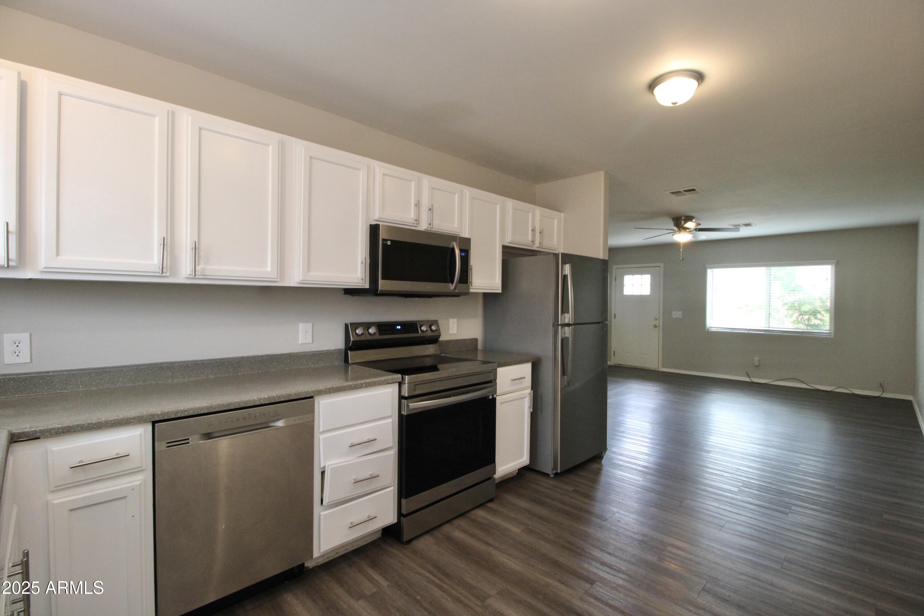 1732 West Maricopa Street, Unit 1 Phoenix, AZ 85007 - Photo 3 of 30 a kitchen with stainless steel appliances granite countertop a stove a sink and white cabinets with wooden floor