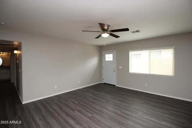 a view of empty room with wooden floor and fan