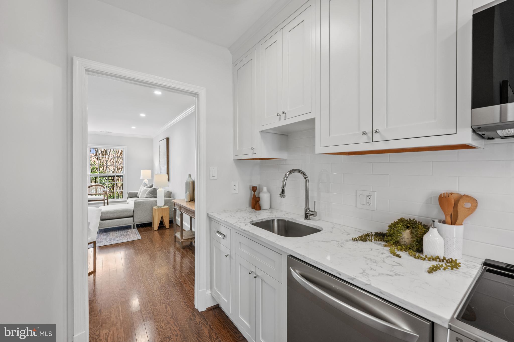 3265 Sutton Place Northwest, Unit B Washington, DC 20016 - Photo 9 of 45 a kitchen with a sink dishwasher stove and white cabinets with wooden floor