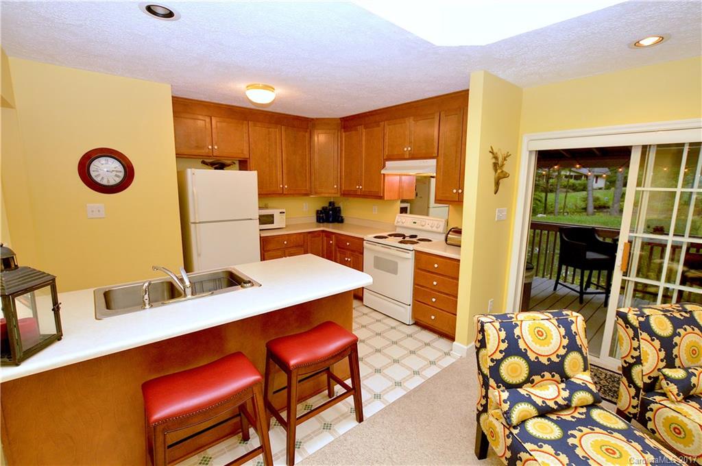 303 Spring Lake Road Maggie Valley, NC 28751 - Photo 4 of 25 a kitchen with refrigerator cabinets dining table and chairs
