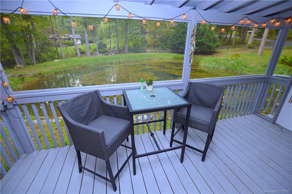 303 Spring Lake Road Maggie Valley, NC 28751 - Photo 5 of 25 a view of a patio with table and chairs under an umbrella with wooden floor and fence