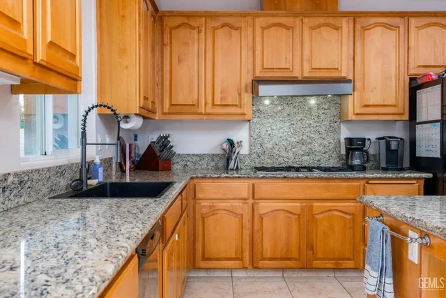 a kitchen with granite countertop a sink a stove and cabinets