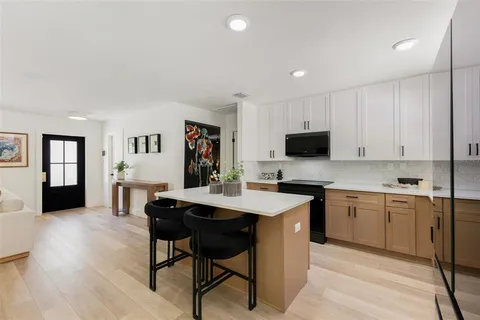 a open kitchen with stainless steel appliances granite countertop a stove a sink dishwasher and a refrigerator with wooden floor