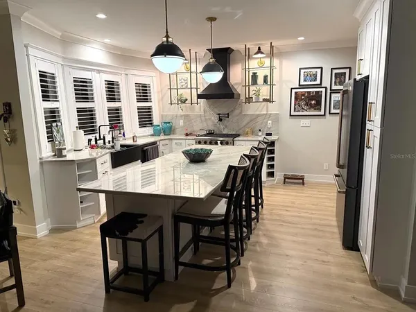 a kitchen with stainless steel appliances granite countertop a stove a refrigerator a sink a dining table and chairs with wooden floor