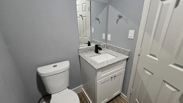 a bathroom with a granite countertop toilet sink and mirror