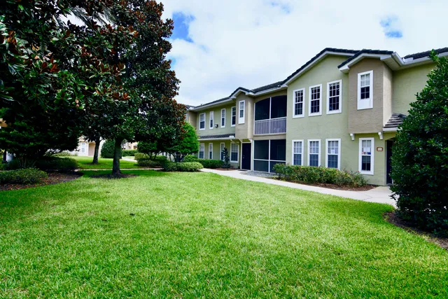 a view of a brick house with a yard and plants