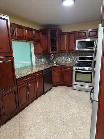 a kitchen with granite countertop stainless steel appliances and wooden cabinets