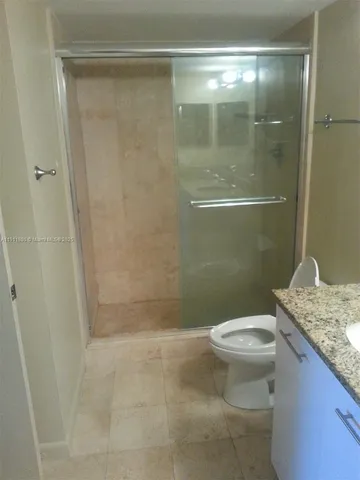 a bathroom with a granite countertop shower a toilet and sink