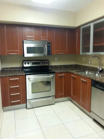 a kitchen with granite countertop a stove top oven microwave and cabinets