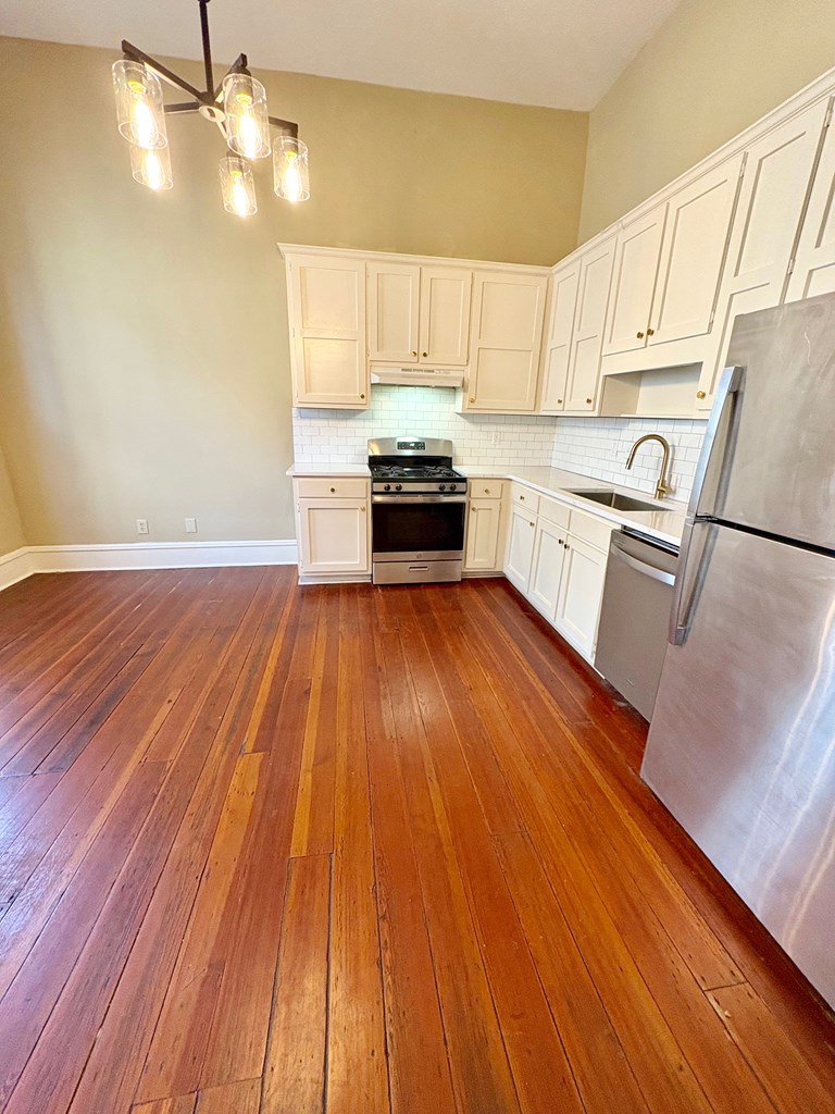 110 7th Street Columbus, GA 31901 - Photo 11 of 24 a kitchen with wooden floors white cabinets and stainless steel appliances