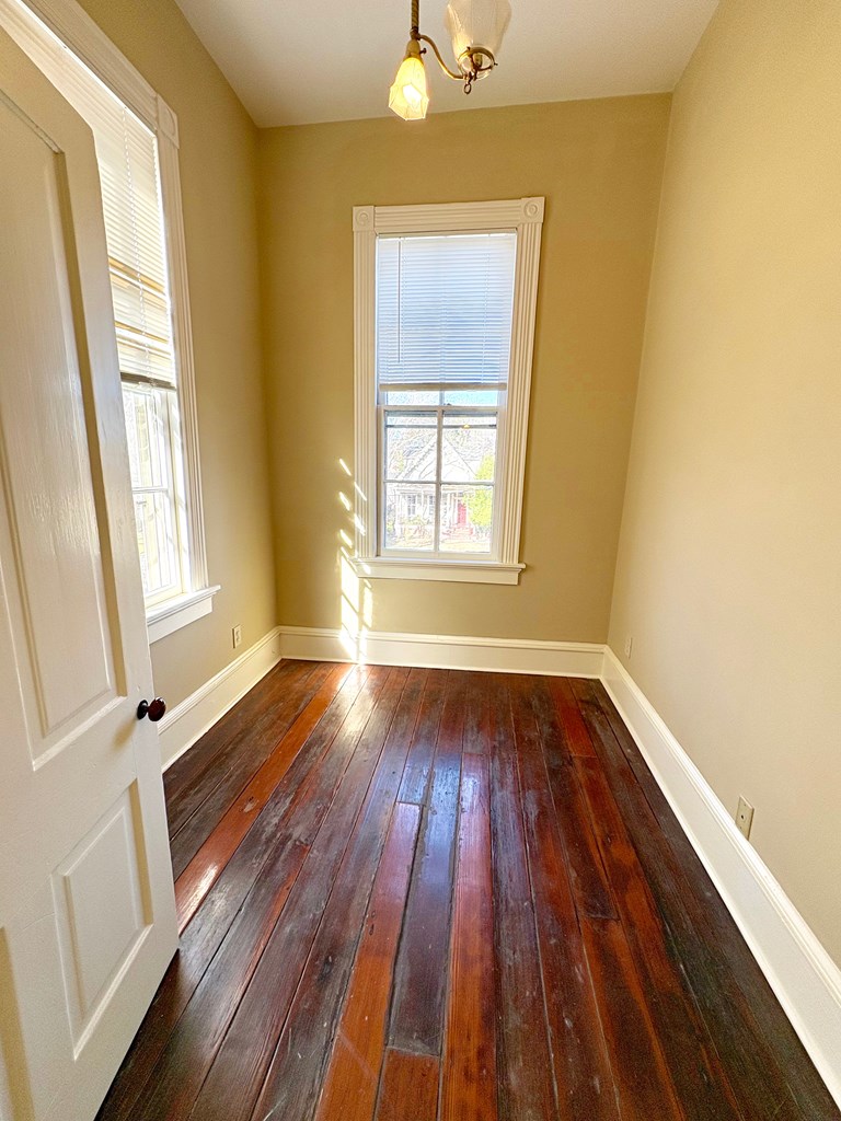 110 7th Street Columbus, GA 31901 - Photo 22 of 24 a view of an empty room with wooden floor and a window