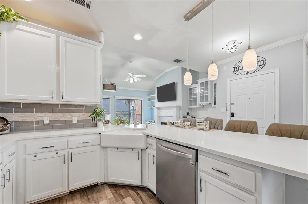 1904 Signal Ridge Place Rockwall, TX 75032 - Photo 12 of 23 Kitchen with white cabinetry, vaulted ceiling, dishwasher, ornamental molding, and light wood-style flooring