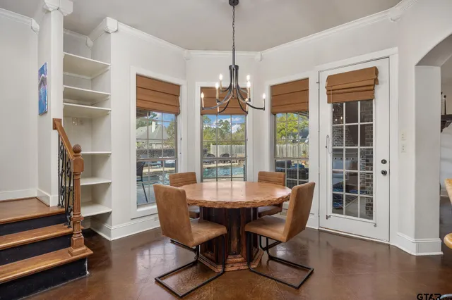a dining room with furniture large windows and a chandelier