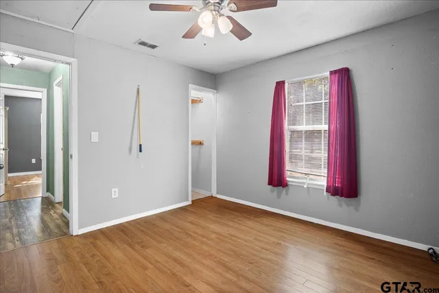 an empty room with wooden floor and windows
