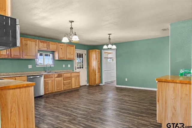 a large kitchen with granite countertop a stove a sink dishwasher and a refrigerator with wooden floor