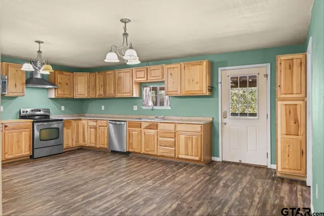a kitchen with granite countertop wooden floors stainless steel appliances and cabinets