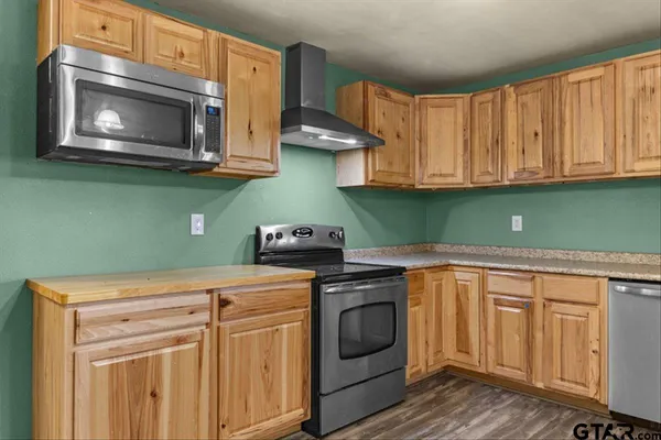 a kitchen with granite countertop a stove top oven microwave and cabinets