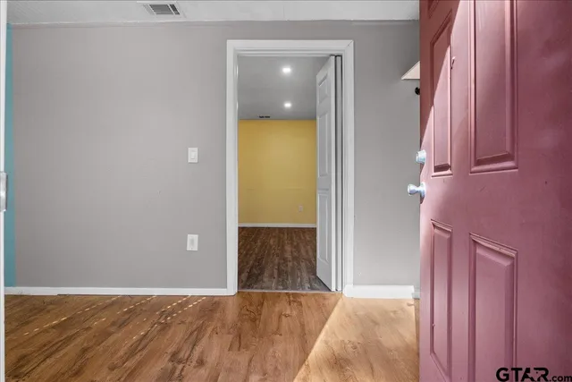 a view of an empty room with wooden floor and a bathroom
